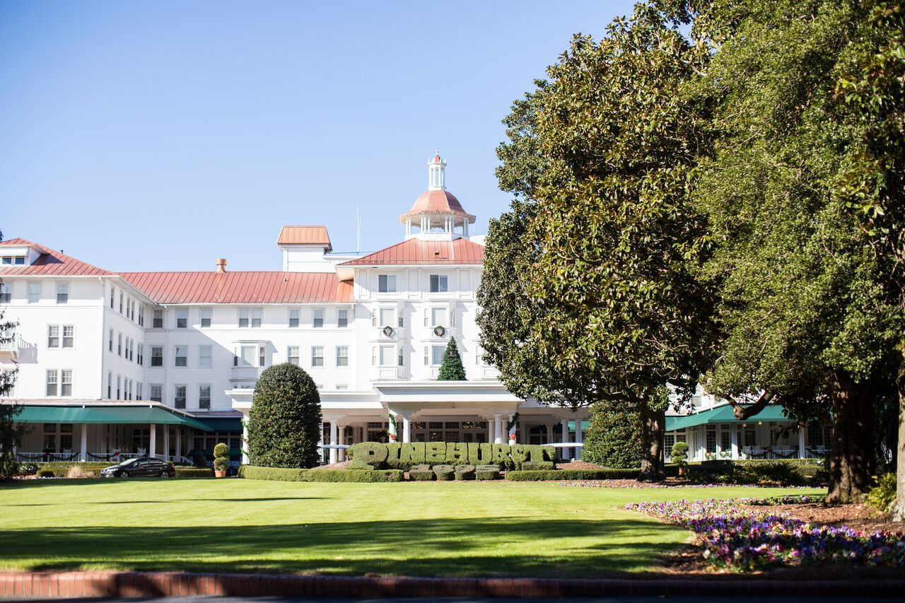 Magnolias and a wide green lawn in front of a white hotel in Pinehurst